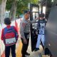 Personel Brimob Polda Kaltim membantu pelajar turun dari bus sekolah gratis di Balikpapan.