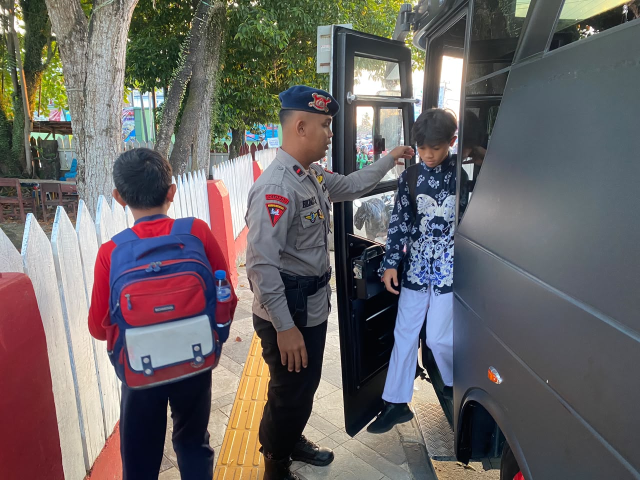 Personel Brimob Polda Kaltim membantu pelajar turun dari bus sekolah gratis di Balikpapan.