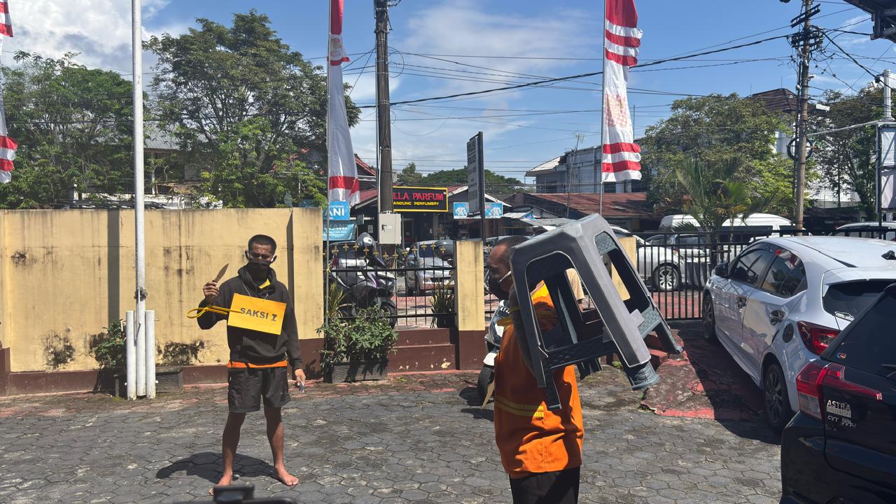 Tersangka memperagakan salah satu adegan saat rekonstruksi kasus duel berdarah yang menewaskan penjaga malam Pasar Sepinggan di Mapolsek Balikpapan Selatan.